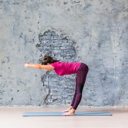 slim woman doing fitness exercise against weathered grey wall