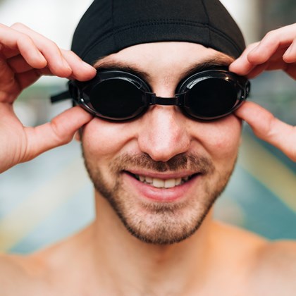 smiley male arranging swimming goggles